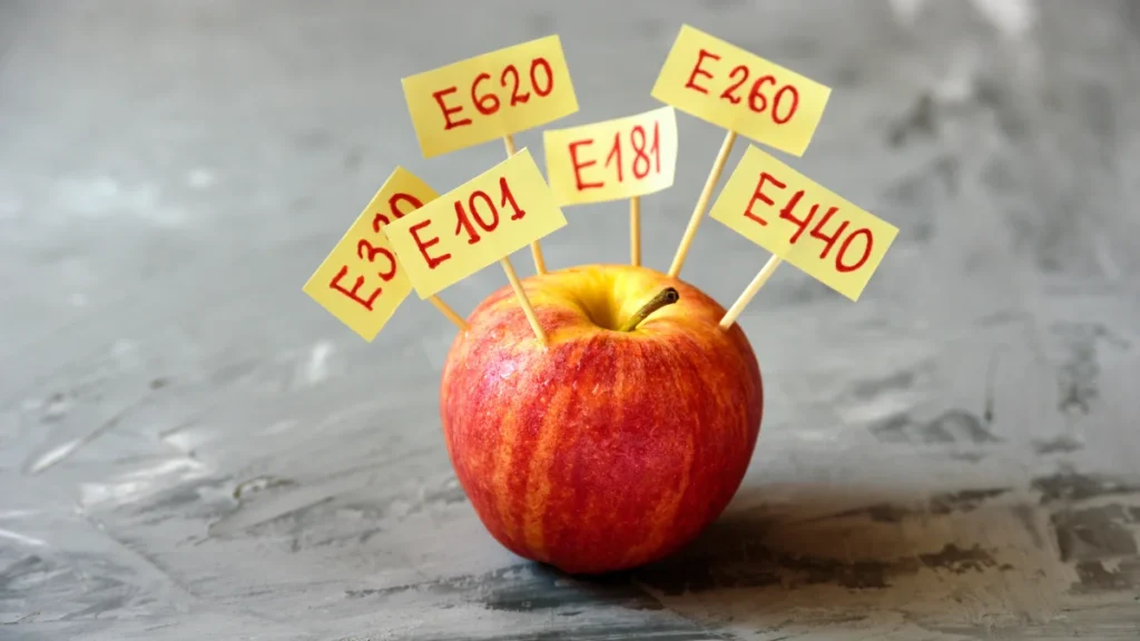 Pomme rouge avec des étiquettes d’additifs comme E101, E620 et E440