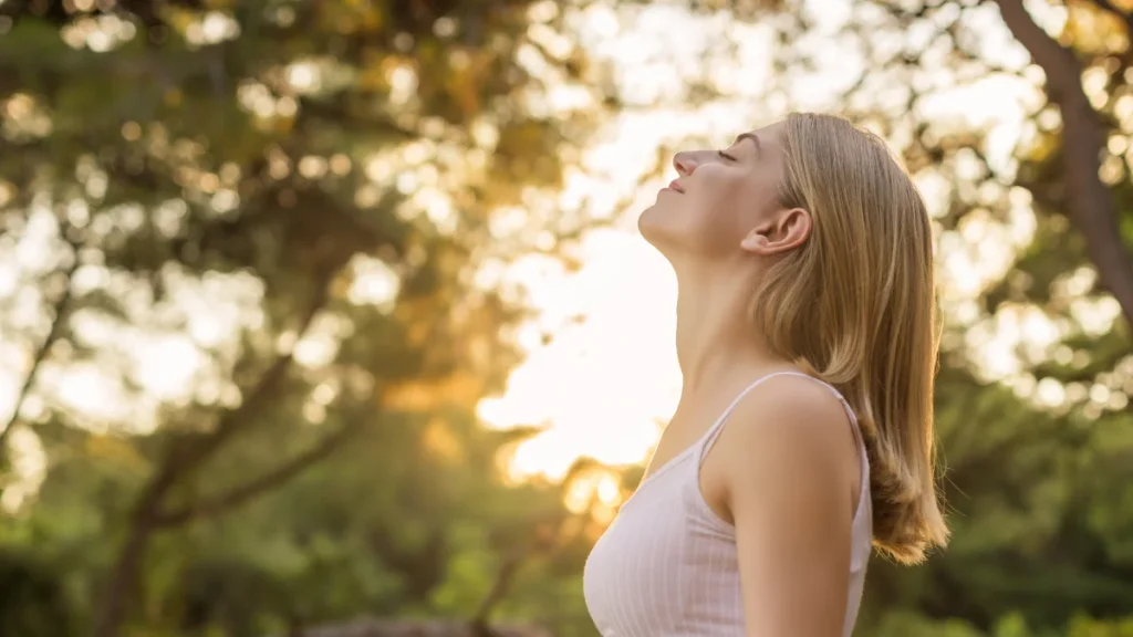 Woman practicing deep breathing in nature for stress relief